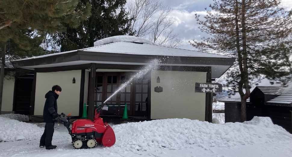 屋根から落ちた雪を除雪機で飛ばしています